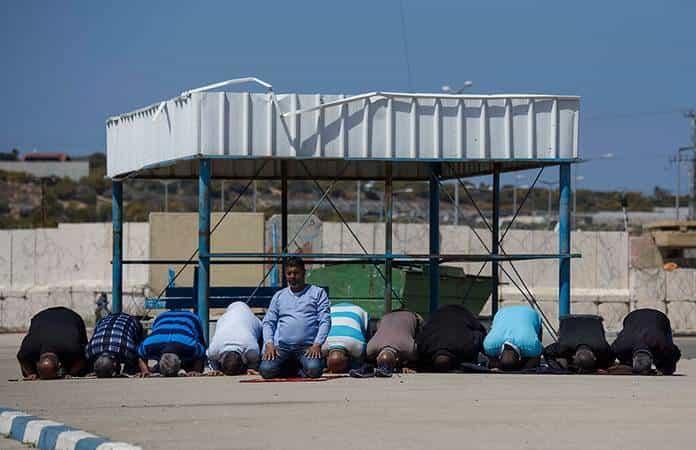 Trabajadores palestinos de Gaza rezan mientras esperan que los israelíes les permitan cruzar la frontera / Foto: AP