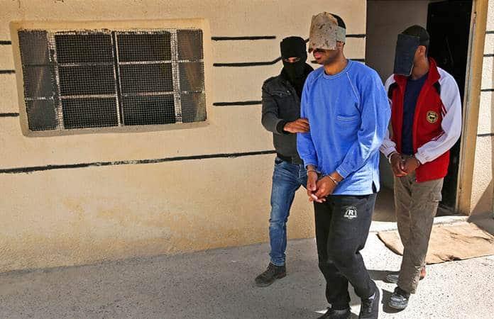 Un agente kurdo traslada a dos prisioneros yihadistas / Foto: AP