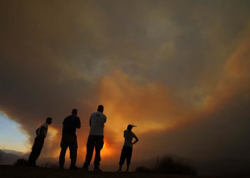 Vecinos de la región de Larnaca miran un incendio en Chipre, que obligó a evacuar al menos tres poblados. (AP Foto/Petros Karadjias)