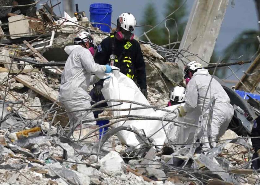 Rescatistas levantan una bolsa que contiene un cadáver en el sitio donde se desplomó el edificio en condominio Champlain Towers South en Surfside, Florida. (AP Foto/Lynne Sladky)