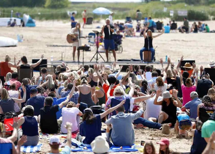Miembros de una iglesia se reúnen en el lago Michigan durante un bautismo este domingo en la playa Montrose, en Chicago.  (AP Foto/Shafkat Anowar)