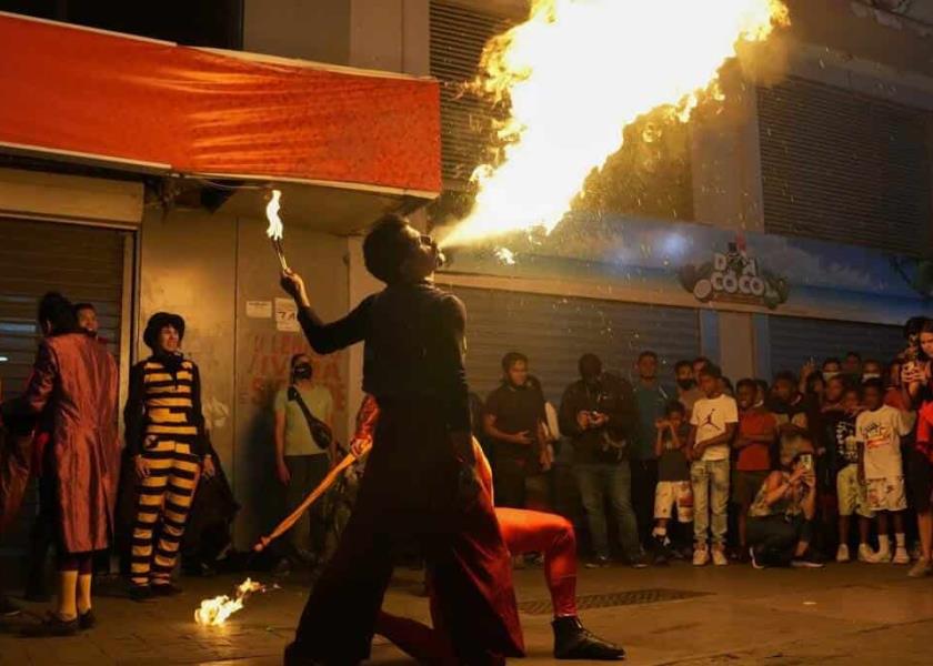 Una persona escupe fuego como parte de los eventos artísticos y culturales de la llamada “Ruta Nocturna”, que incluye menos restricciones en medio de la pandemia de COVID-19, en el centro de Caracas. (AP Foto/Ariana Cubillos)