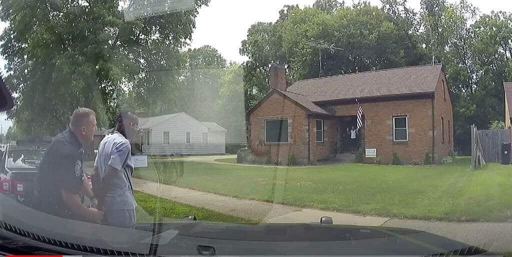 Imagen de la policía de Wyoming, Michigan, muestra a un agente de policía mientras esposa al agente de bienes raíces Eric Brown afuera de la casa que estaba mostrando a un posible comprador. La policía esposo a Brown, a su cliente y al hijo de éste después que un vecino reportara que tres personas afroamericanas habían entrado en la casa en venta. (Departamento de Policía de Wyoming vía AP)