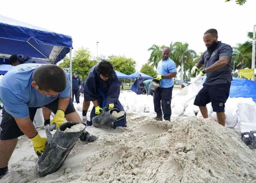 Operarios municipales llenan sacos de arena en un puesto de reparto a residentes antes de la llegada de las lluvias asociadas a la depresión tropical Fred en Grapeland Park, Miami. (AP Foto/Wilfredo Lee)
