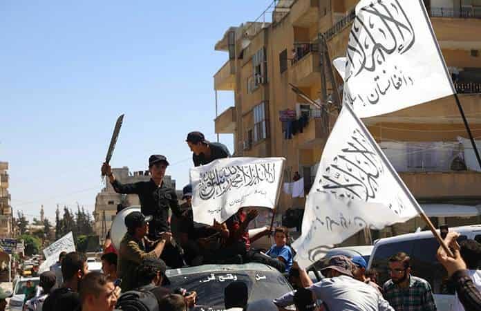 Miembros de una milicia suní ondean banderas del Talibán en la ciudad siria de Idlib / Foto: AP