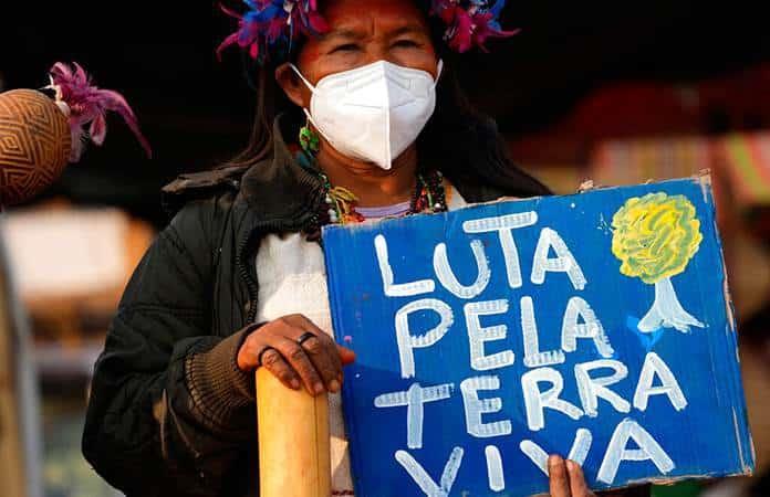 Una indígena sostiene un cartel con la frase «Lucha por la tierra viva» durante una marcha contra Bolsonaro / Foto: AP