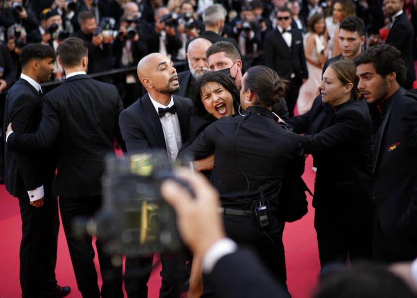 Una manifestante con pintura corporal que dice Dejen de violarnos y los colores de la bandera de Ucrania es retirada de la alfombra roja durante el estreno de la película Three Thousand Years of Longing en la 75ta edición del Festival de Cine de Cannes.